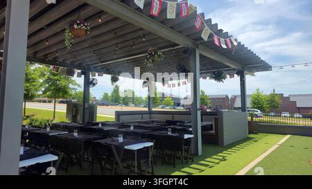 Outdoor restaurant patio with tables set for dining under a covered pergola Stock Photo
