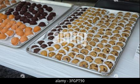 Assorted bite-size cookie dough treats displayed on trays at an outdoor food fair event Stock Photo