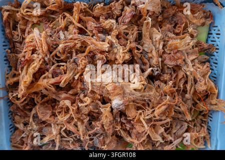 Dried squid tentacles stacked inside blue plastic basket Stock Photo