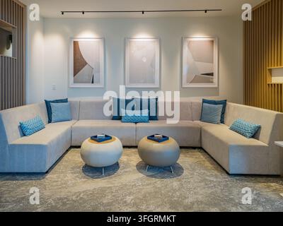 Arkansas, United States, SEP 05, 2026 - A spacious interior features a large beige sectional sofa with blue pillows facing two round coffee tables on Stock Photo