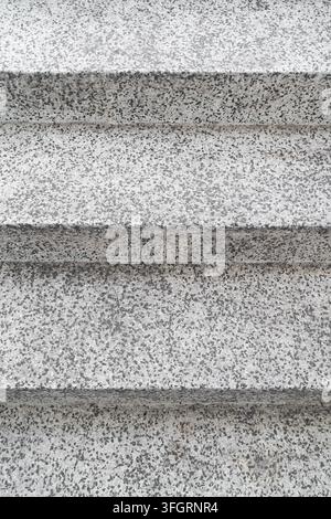Close-up abstract view of a speckled concrete or terrazzo surface with horizontal stepped layers, creating a monochromatic gray architectural texture Stock Photo