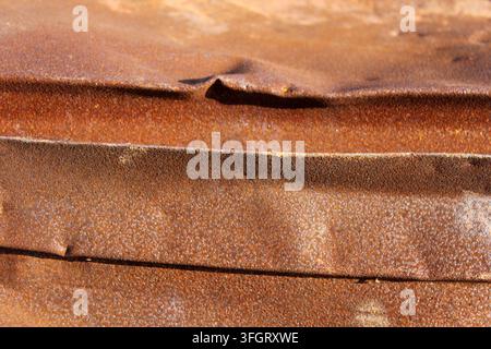 Close-up of a dented and heavily rusted corrugated metal sheet showing an orange-brown weathered patina Stock Photo
