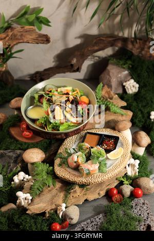 Fresh Salad and Vietnam Spring Rolls arranged on rustic, natural elements. Mushrooms, greens, and tomatoes add texture and color. Earth tones and orga Stock Photo