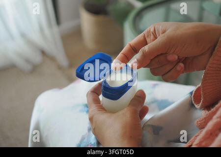 a young woman applying petroleum jelly while sitting on bed Stock Photo