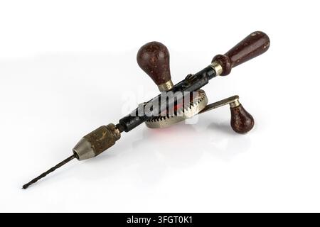 Vintage hand operated manual drill, The hand cranked drill is made of metal and wooden parts and is seen here on a white background Stock Photo