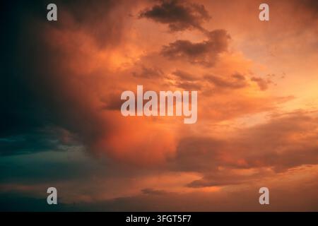 Dramatic storm clouds glowing orange and red beneath intense evening light, with dark turbulent formations creating a powerful atmospheric sky. Severe Stock Photo