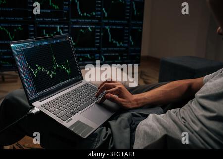 Close-up of trader analyzing real-time stock market data and financial charts on laptop, closely monitoring multiple screens with cryptocurrency trend Stock Photo