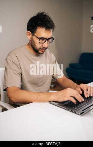 Vertical portrait of focused programmer male working typing code on laptop keyboard, showcasing process of software development and coding expertise. Stock Photo
