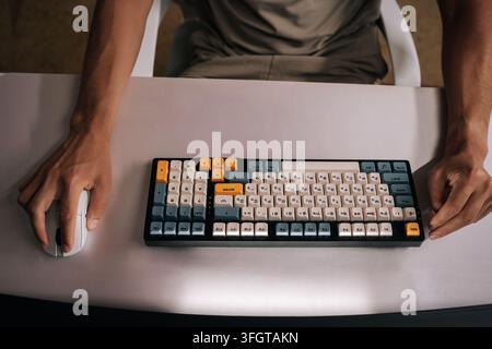 Close-up top view of programmer hands engaging with vibrant mechanical keyboard and mouse on desk, capturing essence of programmer or gamer immersed Stock Photo