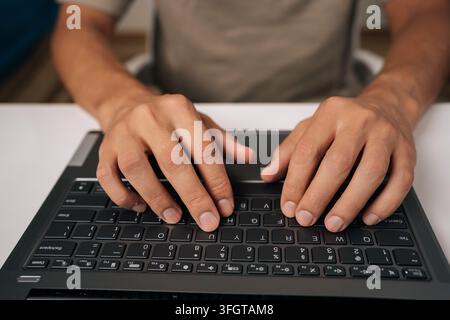 High-angle view of unrecognizable programmer male typing code on laptop keyboard, showcasing process of software development and coding expertise Stock Photo