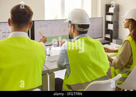Engineers Monitoring Industrial Operations on Several Screens in Modern Control Room Stock Photo