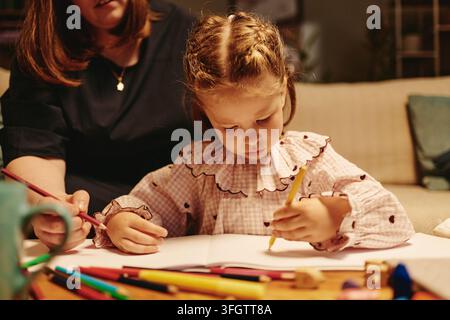 Girl Drawing with Colored Pencils in Notebook with Mother Stock Photo