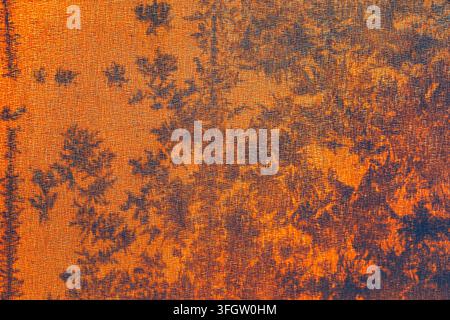 Woven fabric fibers covered in frost crystals forming branching, fern-like patterns. Backlighting produces warm gradient across textured surface Stock Photo