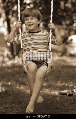 Child sitting on a swing smiling Stock Photo