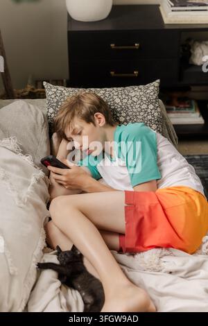 Boy lounges on couch using his smartphone Stock Photo