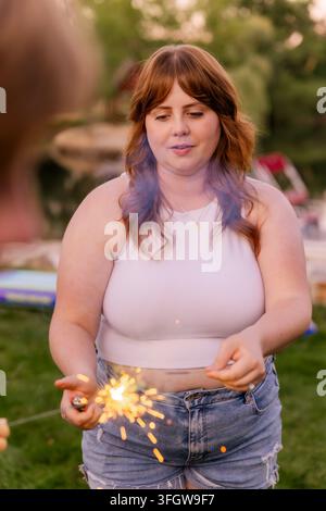 Young woman lighting a sparkler in backyard Stock Photo