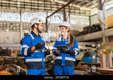 Factory Technicians Male and Female Talking Discussion Working together in Dirty Grunge Heavy Equipment Warehouse. Stock Photo