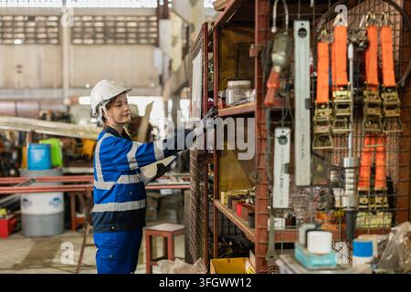 Female Technician Checking Organizing Spare Parts Shelf In Old Heavy Machinery Warehouse. Stock Photo