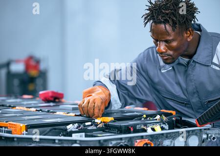 EV battery service mechanic working electric car lithium ion Battery pack maintenance garage. Electric car technician performs maintenance on car batt Stock Photo
