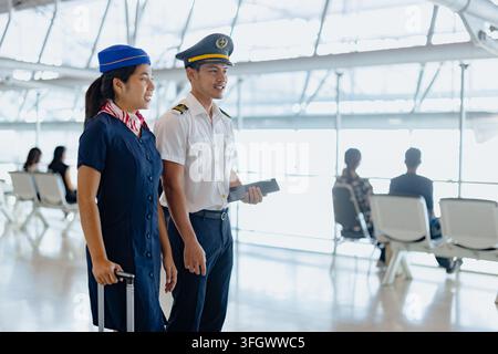 Asian Pilot Smiling Walking Friendly Talking with Female Air Hostess in Airport Terminal Background, Thai Flight Crew Conversation Cabin Attendant Air Stock Photo