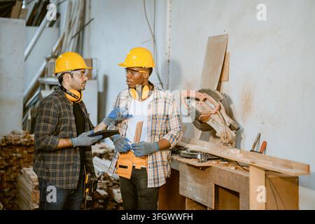 Two Male African Black Carpenters Workers Standing Together Examining Wooden Plank Inspection Quality Control Inside Furniture Factory Workshop Site Stock Photo