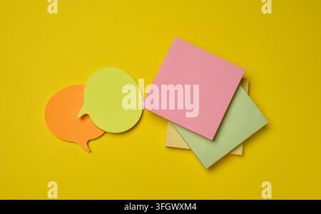 Multicolor sticky notes of various shapes and speech bubbles on a bright yellow background. Stock Photo