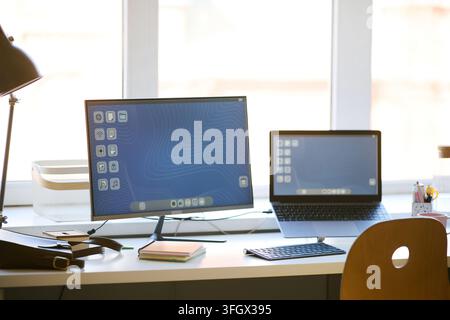 Home office workstation displaying desktop monitor and laptop, supporting multitasking and digital productivity. Ideal for remote work, hybrid work, t Stock Photo