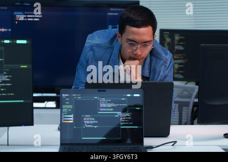 Focused programmer working on software development, digital technology, artificial intelligence, and cybersecurity code using a laptop. Stock Photo