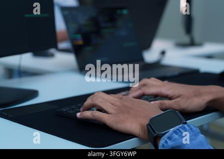 Developer hands typing on a laptop keyboard while working with digital code, software development, programming, and artificial intelligence technology Stock Photo
