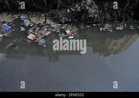 Dhaka, Bangladesh - 14 September 2026: View of polluted water in a canal filled with plastic waste and debris in the city. Stock Photo