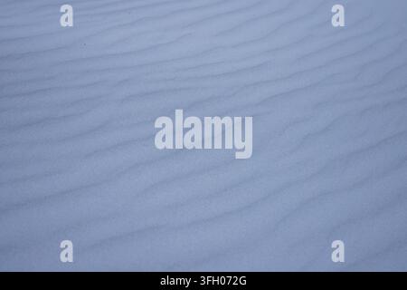 Fine-grained rippled sand surface is stretching diagonally in close-up dune scene, bluish tint Stock Photo