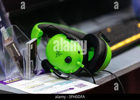 Cologne, Germany - August 26, 2026: Razer gaming headset in bright green color placed on a table with promotional flyers and a keyboard visible in the Stock Photo