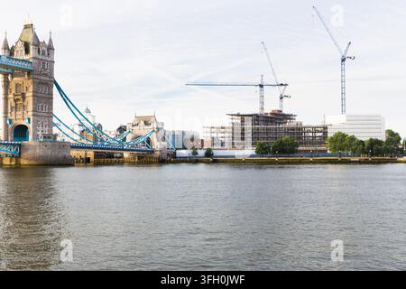 Cranes work over London's River Thames, constructing a new building One Tower Bridge  near the historic Tower Bridge for urban development. Stock Photo
