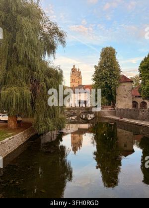 St. Stephen's Parish Church, Francoski Most and a large weeping willow reflected in the river in the historic center of Ribnica, Slovenia, at golden h Stock Photo