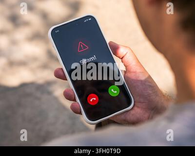 Scam call warning on smartphone alerts user to phone fraud, vishing, caller spoofing and identity theft risk, mobile cybersecurity and consumer protection. Stock Photo