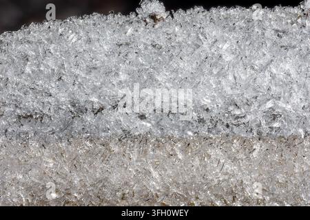Extreme close-up reveals intricate needle-like ice crystal structures layered across a frozen surface, showing translucent angular formations with gli Stock Photo