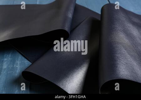 Luxury fashion and craftsmanship, dark blue leather material with smooth texture for high-end accessories and upholstery design on a wooden surface Stock Photo