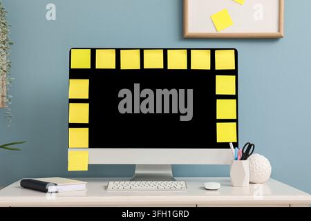Workload management and deadline pressure, computer monitor covered with yellow sticky notes for task organization and project planning in home office Stock Photo