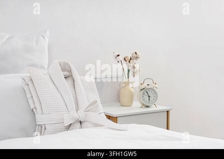 Folded waffle bathrobe on bed in room Stock Photo
