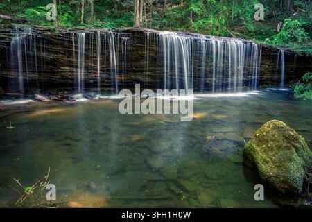 Princess Falls cascades over a broad rock ledge into a forest pool surrounded by lush late-spring foliage in Daniel Boone National Forest in the Big S Stock Photo