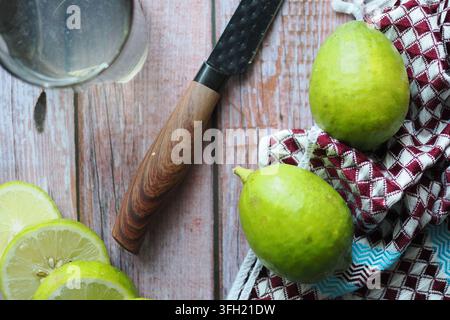 Lemons and limes on a wooden table with a knife and cloth Stock Photo