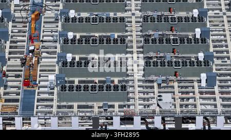 Data center roof showing extensive cooling infrastructure with numerous air conditioning units and piping Stock Photo