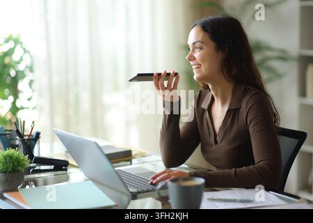 Happy office worker using ai voice recognition on phone working online Stock Photo