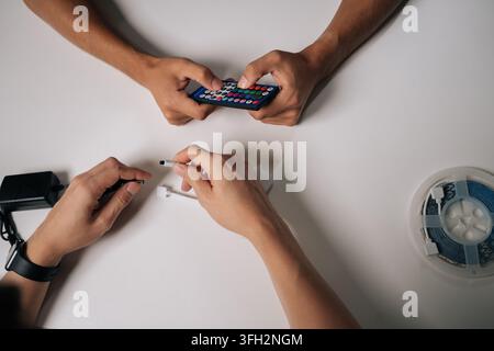 Two technicians connecting RGB led strip lights using remote control and controller, adjusting backlight settings for customized illumination. Stock Photo