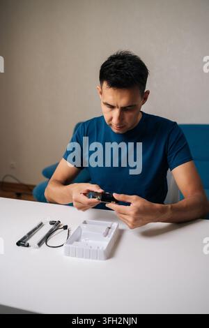 Vertical shot of technician male assembling wi-fi module using tools at home office desk, focusing on intricate components and ensuring proper Stock Photo