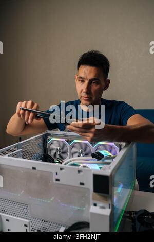 Vertical portrait of computer technician inserting wireless network module inside custom desktop computer, enhancing system connectivity for reliable Stock Photo