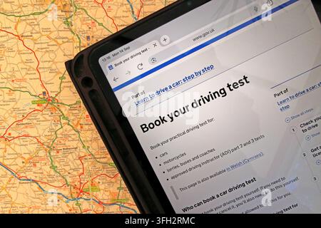 GOV.UK 'Book your driving test' service on an iPad over a road map, illustrating online practical-test booking in England. Stock Photo