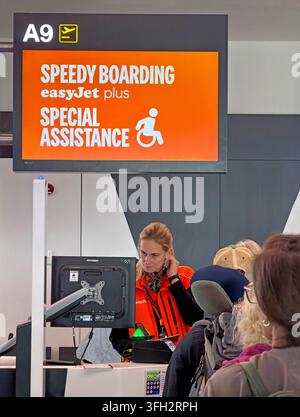 easyJet Speedy Boarding and Special Assistance sign at an airport gate, with passengers waiting at the staffed boarding desk. Stock Photo