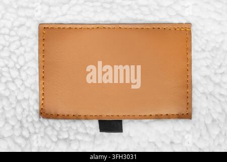 Blank yellow leather patch label stitched on white fleece background Stock Photo