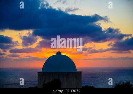 Holy Family Chapel at Stella Maris on Mount Carmel, Haifa, Israel, silhouetted against a dramatic sunset over the Mediterranean Sea. Stock Photo